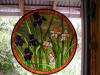 Stained glass window hanging with irises and daffodils.